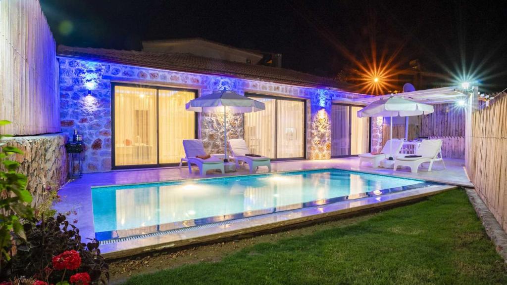 a swimming pool with chairs and umbrellas at night at villa vera in Kalkan