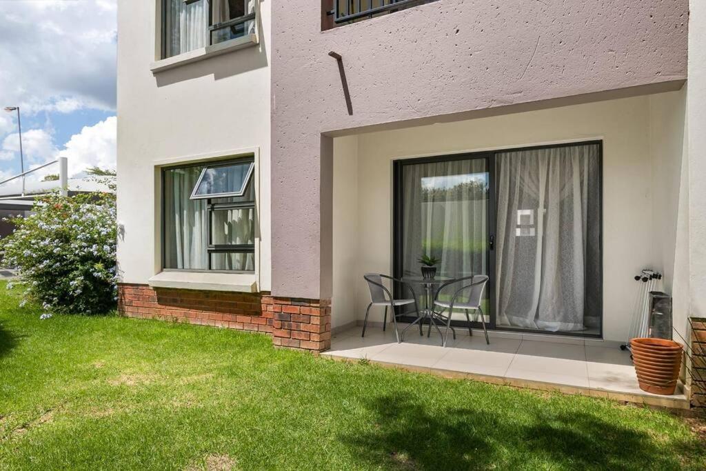 eine Terrasse eines Hauses mit einem Tisch und Stühlen in der Unterkunft V&S Apartments - Lovely 2 bedroom in Fourways, Johannesburg in Midrand