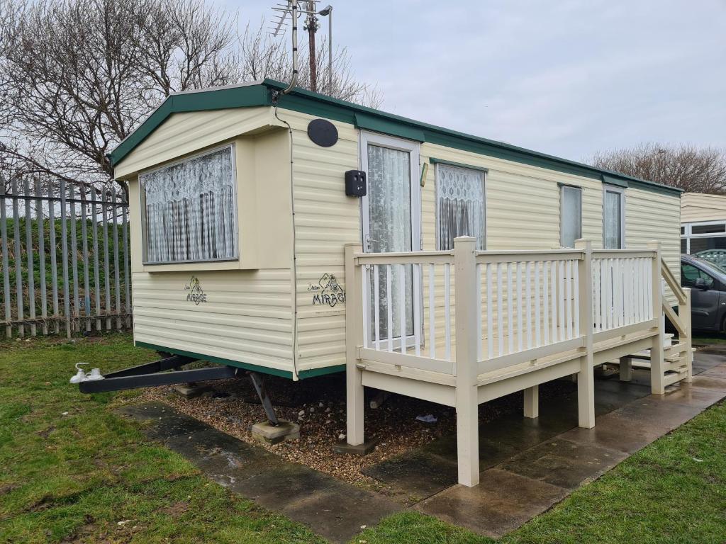 a tiny house with a porch and a fence at 6 Berth Promenade Ingoldmells (Mirage III) in Ingoldmells