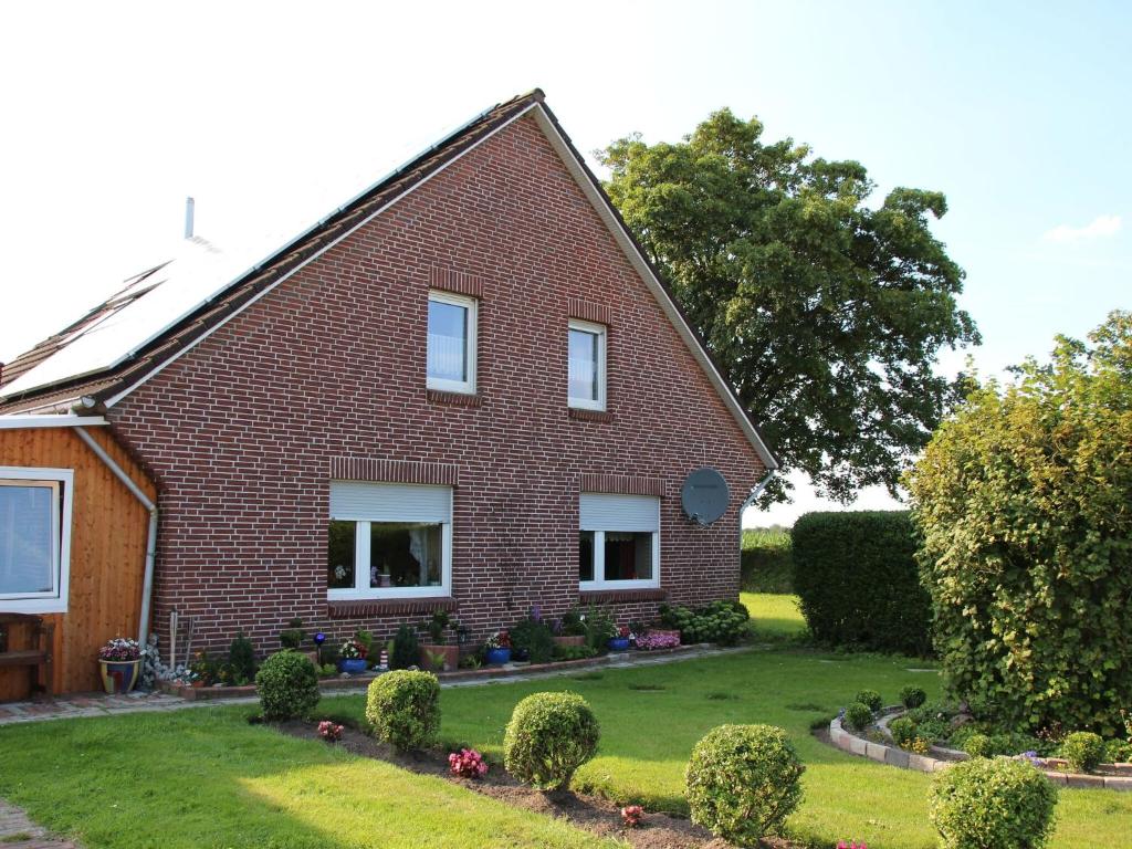 a red brick house with a green yard at Apartment, Essen in Esens