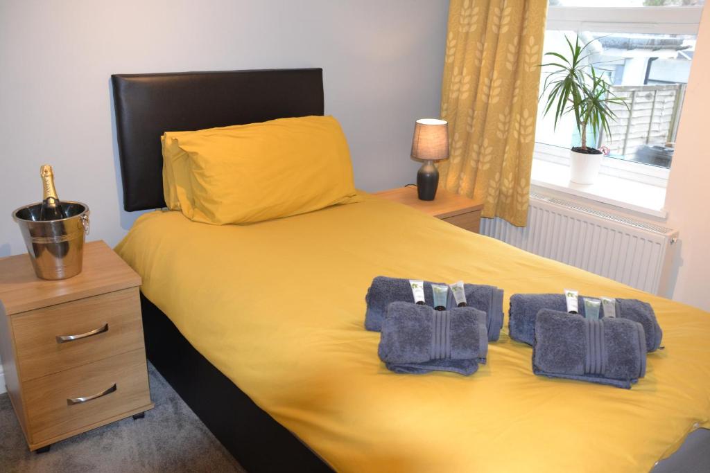 a bedroom with a yellow bed with towels on it at Olive Tree Apartment - 2 Bedrooms Apartment - Stayseekers in Salisbury