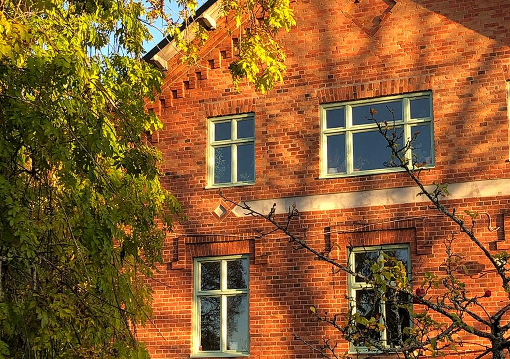 a red brick building with three windows on it at FärgLabbets Bed and Breakfast in Sunne
