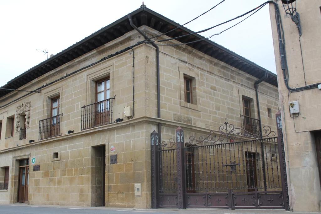 un ancien bâtiment en briques avec un portail et une clôture dans l'établissement EL REAL DE SIOTA, à Castañares de Rioja