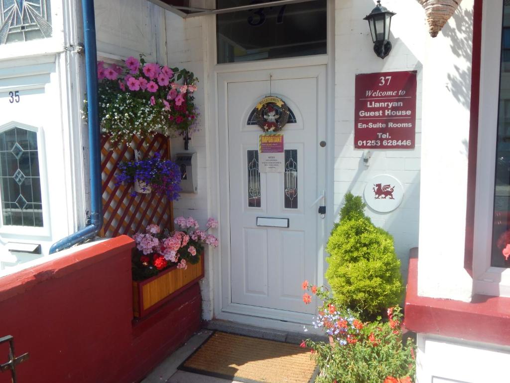 Una puerta blanca de un edificio con flores. en Llanryan Guest House, en Blackpool