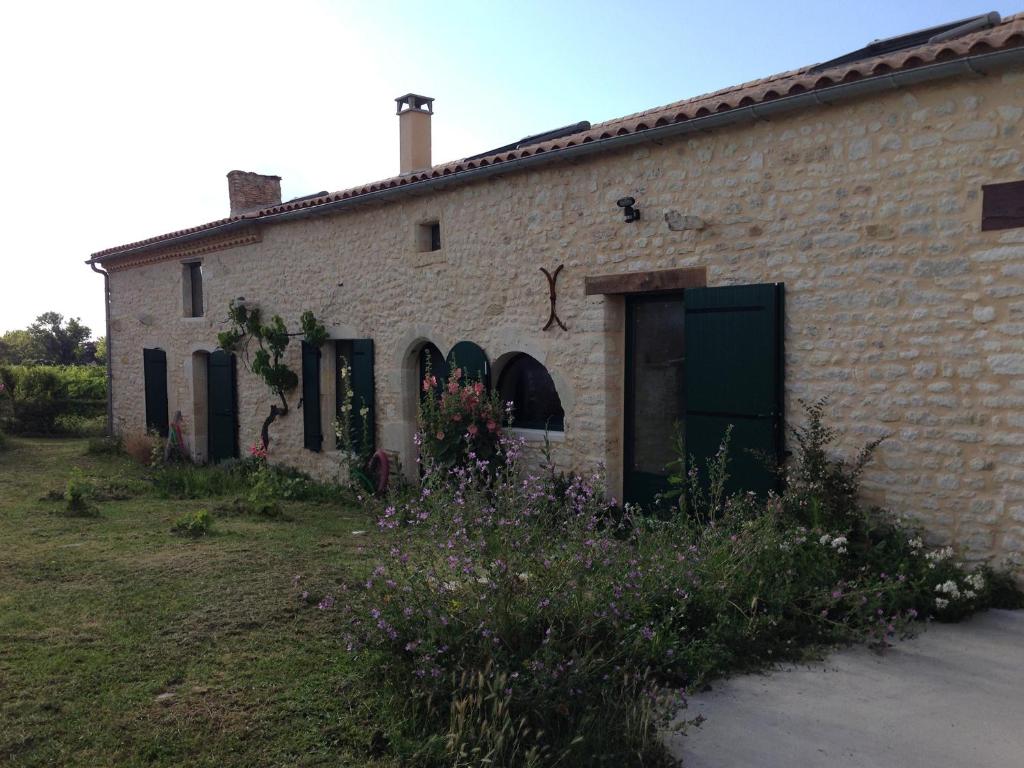 un antiguo edificio de ladrillo con una puerta verde y flores en Chai Crann Piorra 1 en La Valade