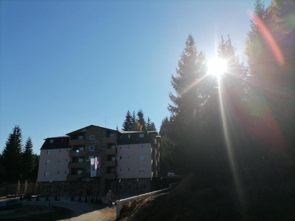 新瓦罗什Apartman Zlatar Omiljena的阳光照耀着树的建筑