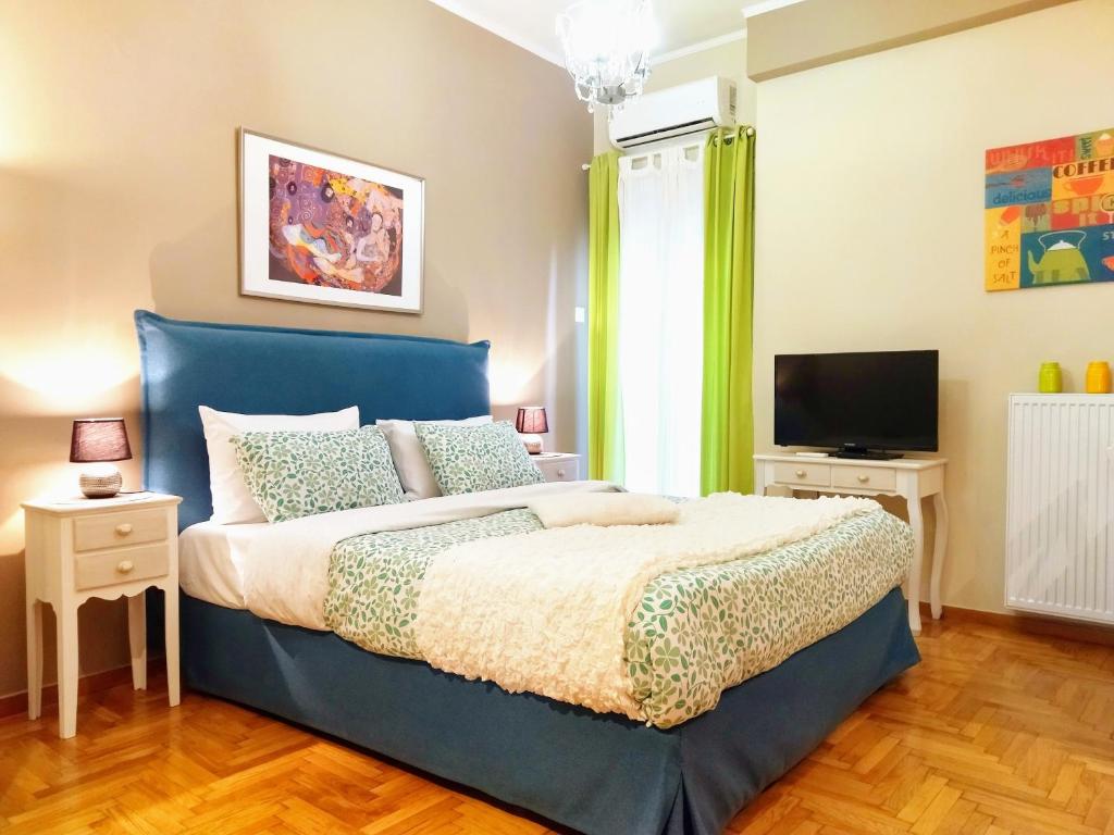 ein Schlafzimmer mit einem blauen Bett und einem TV in der Unterkunft City Stay Alexandras Av. in Athen