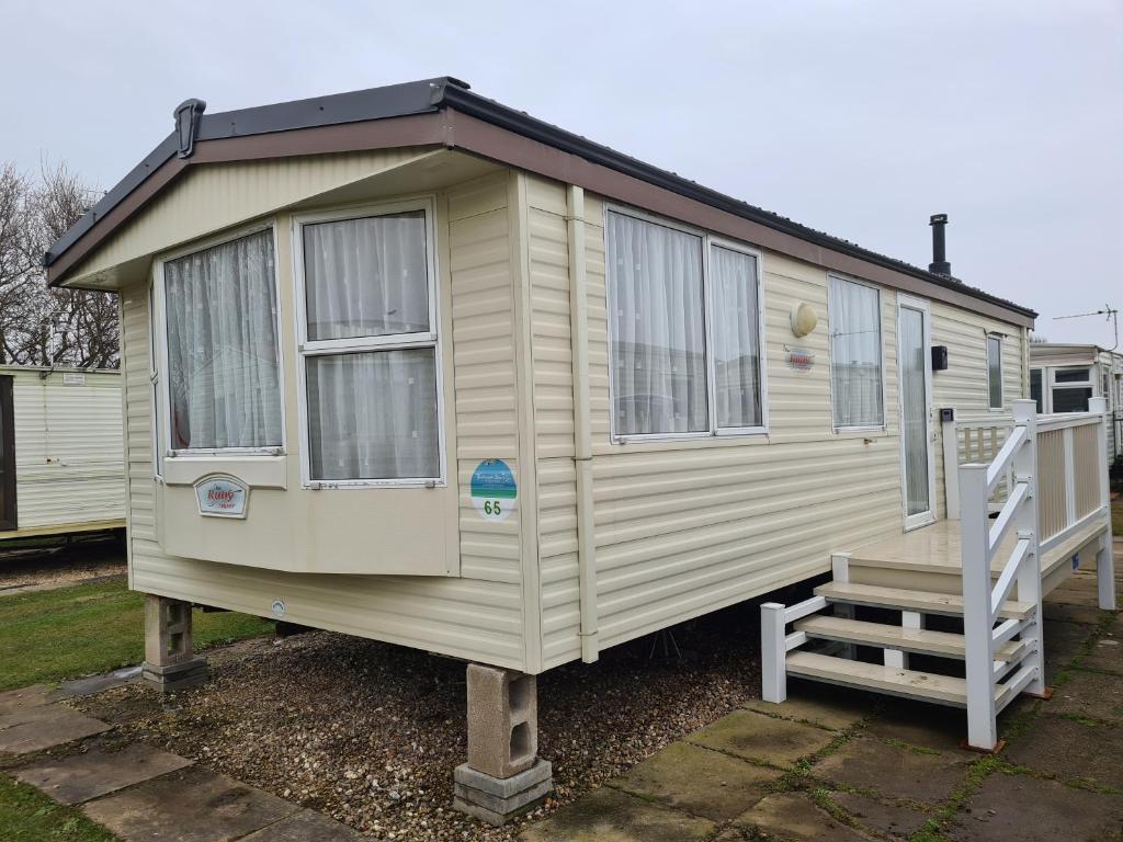 a yellow tiny house with a porch and a staircase at 6 Berth Promenade Ingoldmells (Ruby) in Ingoldmells