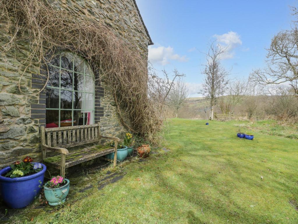 a stone building with a bench in a yard at Beudy Dolpebyll in Llangadfan