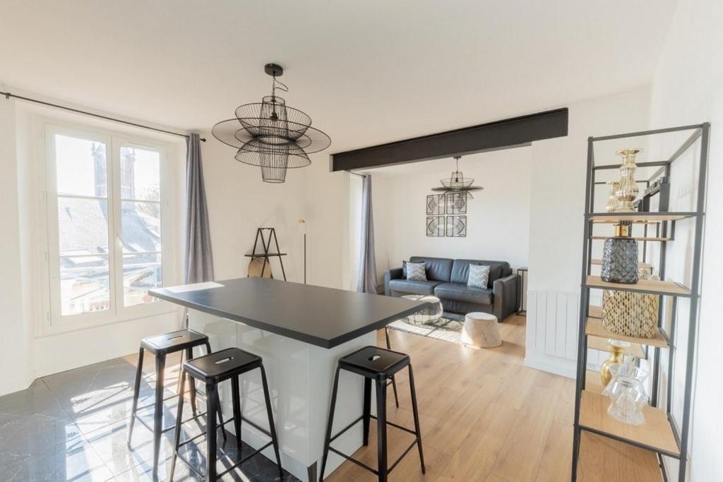 a kitchen and living room with a table and stools at Villa des Arts in Épernay