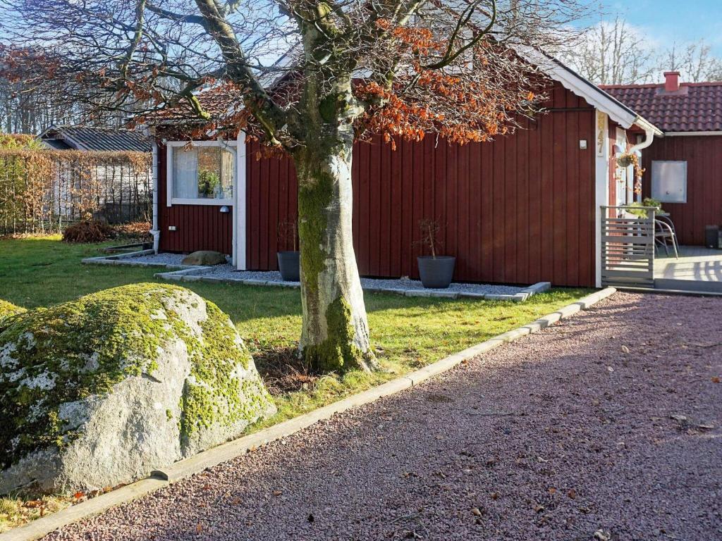 un árbol frente a una casa con una roca en Holiday home SÖLVESBORG XV, en Sölvesborg