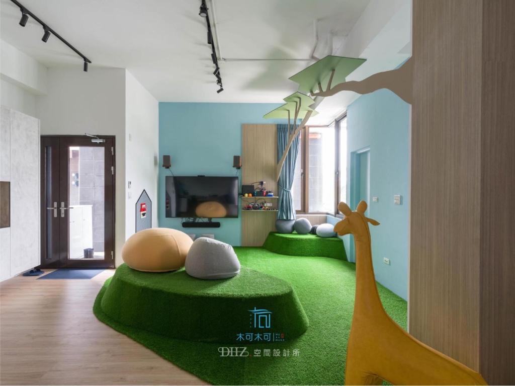 una sala de estar con una jirafa sentada sobre una alfombra verde en Muco Muco Bnb, en Yilan City