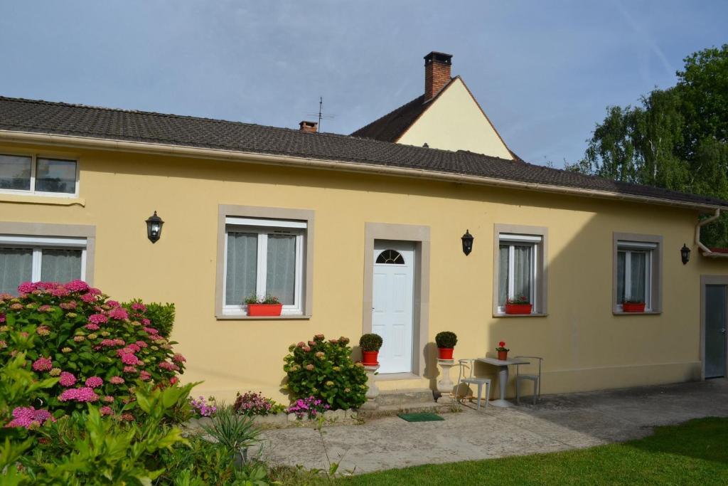 een geel huis met bloemen ervoor bij L'Araucaria in Pontault-Combault