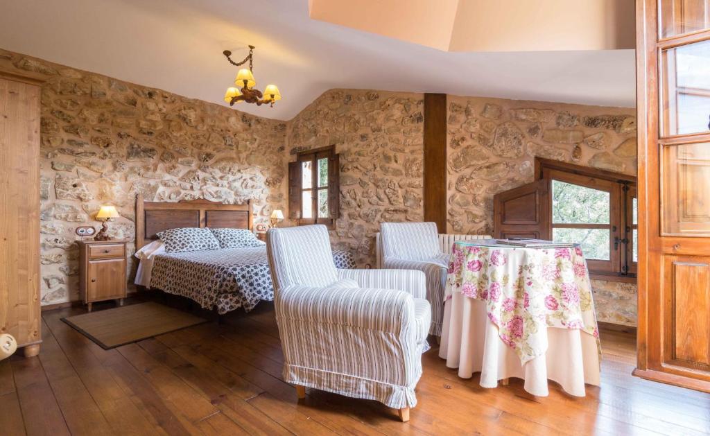 1 dormitorio con 1 cama y 2 sillas en Hotel de Montaña Cueva Ahumada, en Villaverde de Guadalimar