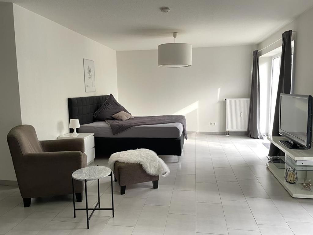 uma sala de estar com uma cama e uma cadeira e uma televisão em Modernes Appartement em Gladbeck