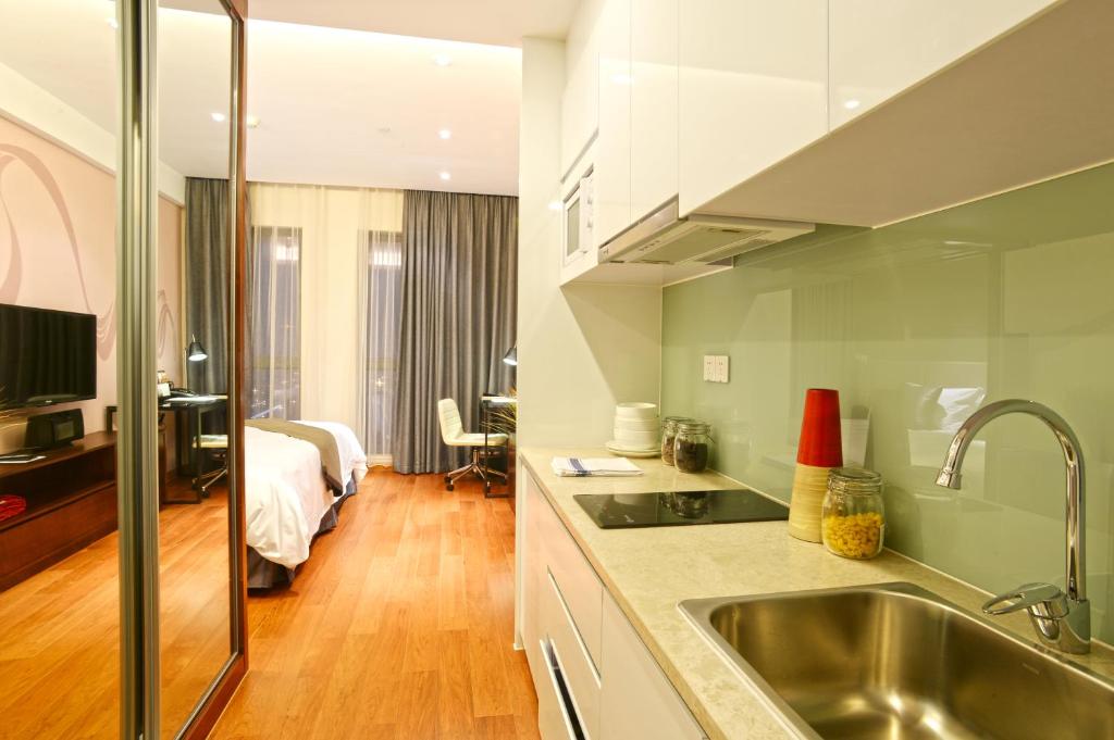 una cucina con lavandino e una camera con letto di Modena By Fraser New District Wuxi a Wuxi