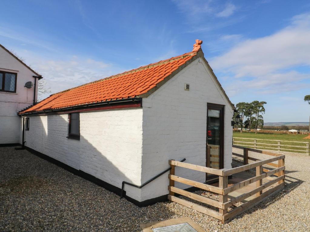 ein kleines weißes Gebäude mit orangefarbenem Dach in der Unterkunft Cowshed Cottage in Malton