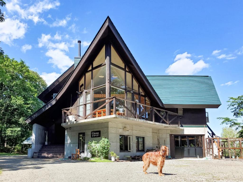 a dog standing in front of a house at Pension Gooseberry in Furano