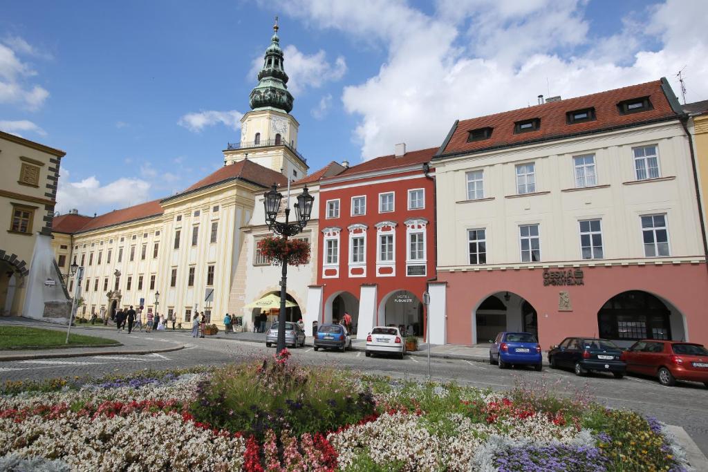 un edificio con una torre de reloj y coches aparcados en la calle en Hotel Purkmistr, en Kroměříž