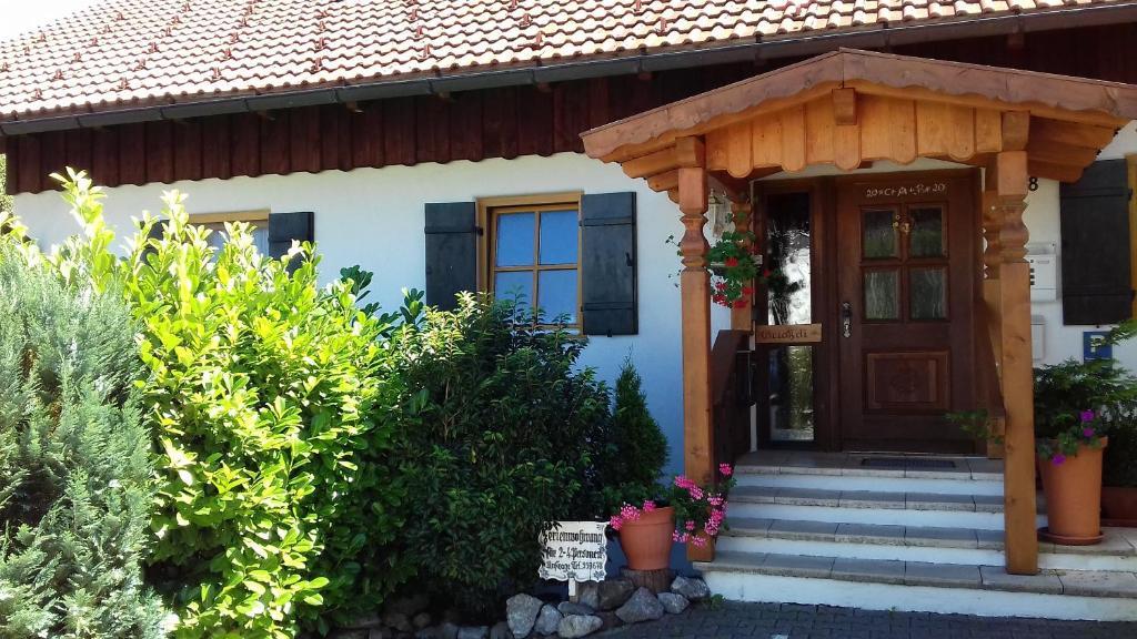 ein Haus mit einer Holztür und einer Veranda in der Unterkunft Ferienwohnung Engelhardt in Oberreute