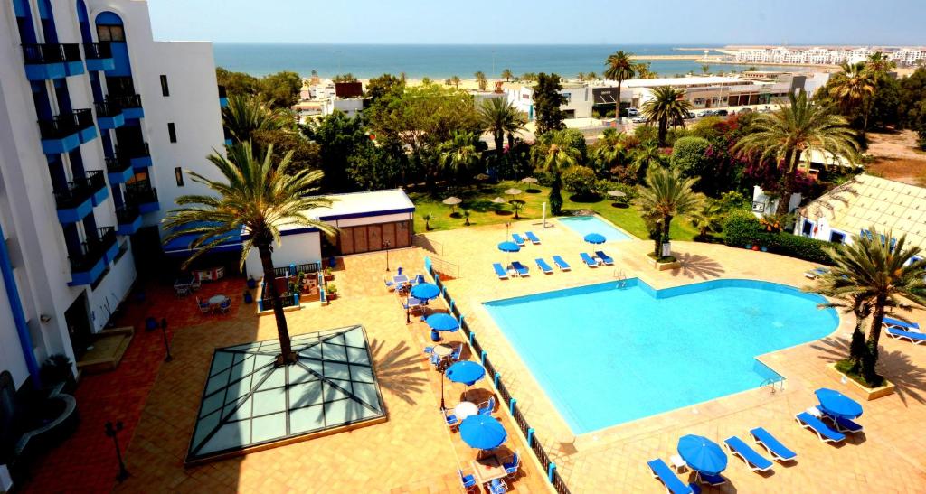 uma vista sobre uma piscina com cadeiras e palmeiras em Oasis Hotel & Spa em Agadir
