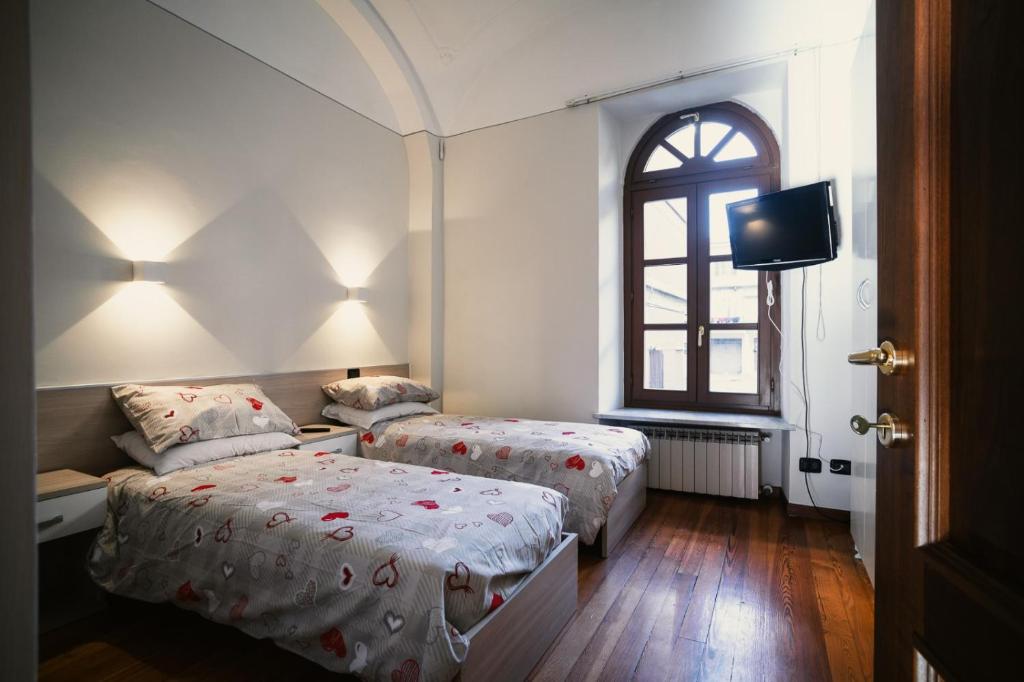 1 dormitorio con 2 camas, TV y ventana en La Locanda del Bistrot dei Vinai, en Cuneo