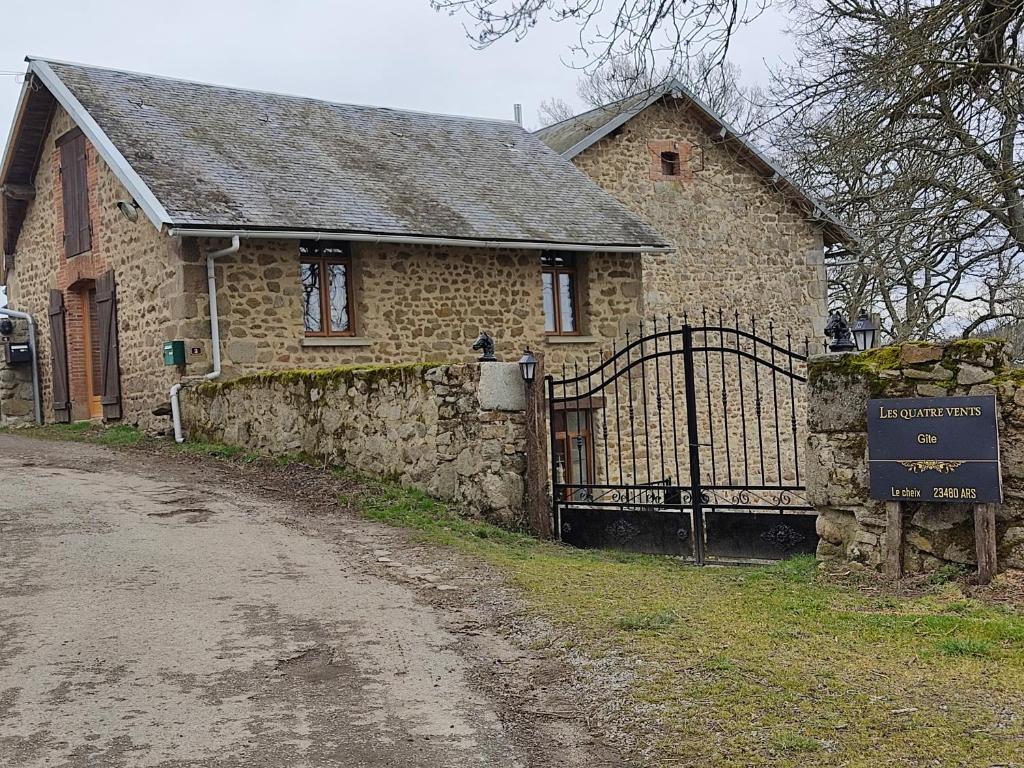 ein Steinhaus mit einem Tor neben einer unbefestigten Straße in der Unterkunft Les quatre vents in Ars