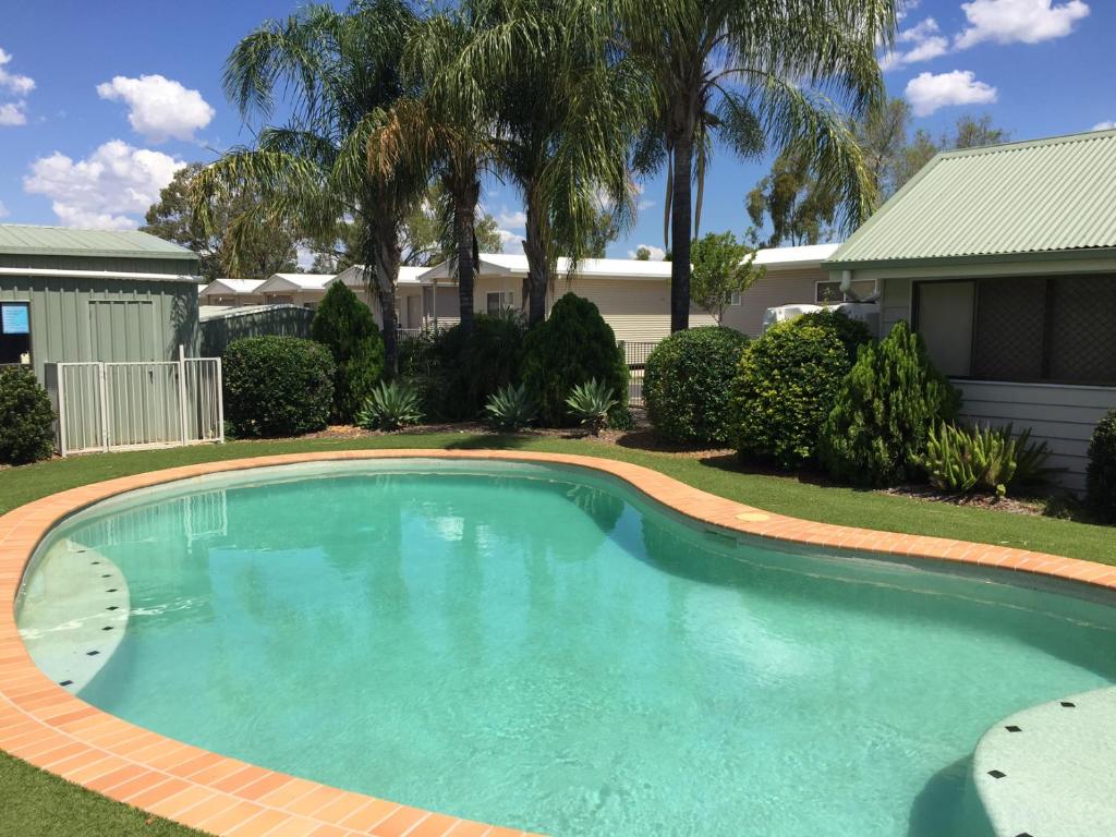 a swimming pool in a yard with a house at Chinchilla Tourist Park in Chinchilla