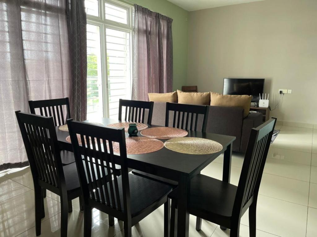 a dining room with a table and chairs and a couch at LA 1 Homestay Putrajaya Dwiputra in Putrajaya