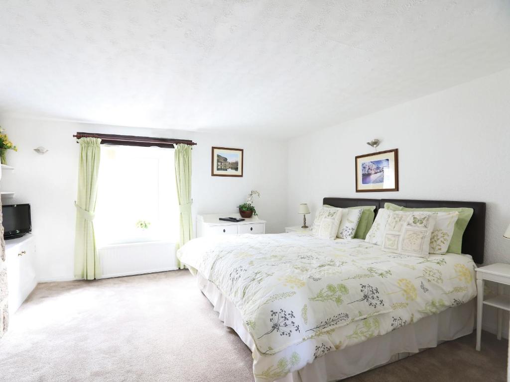 a white bedroom with a large bed and a window at The Willow Bed and Breakfast in Pateley Bridge