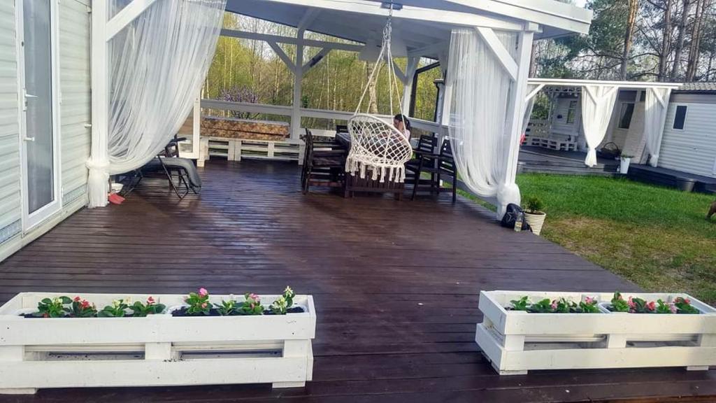 a porch with two white planters with flowers on it at Domki Holenderskie Mazury Leleszki in Leleszki