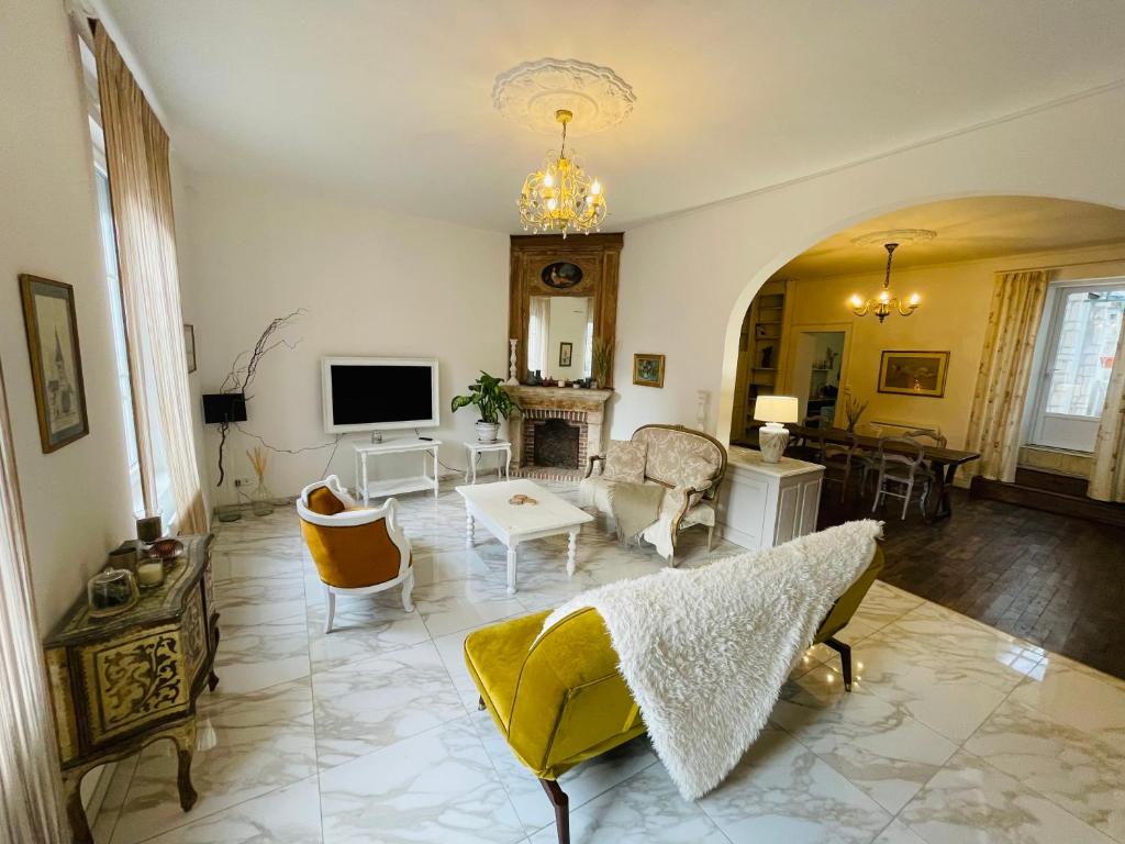 ein Wohnzimmer mit einem Sofa und einem TV in der Unterkunft Magnifique maison d’artiste in Reims