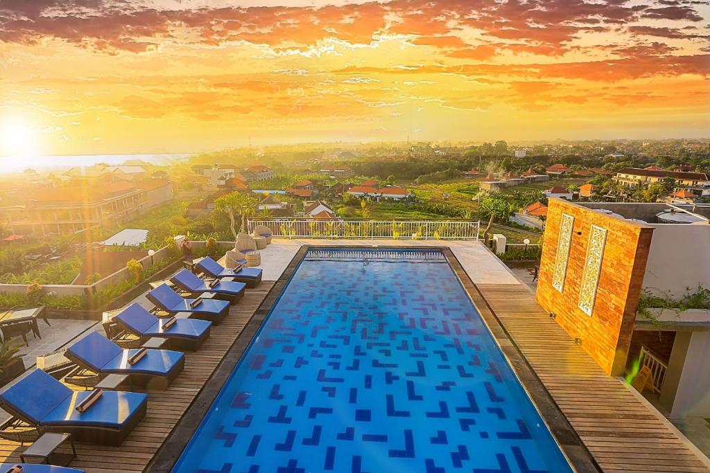 a swimming pool with lounge chairs on top of a building at Canggu Dream Village Hotel and Suites in Canggu
