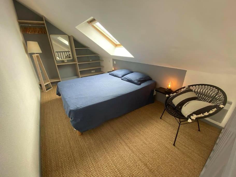1 dormitorio con 1 cama azul y 1 silla en Joli appartement 4 personnes - vue mer en Ploemeur