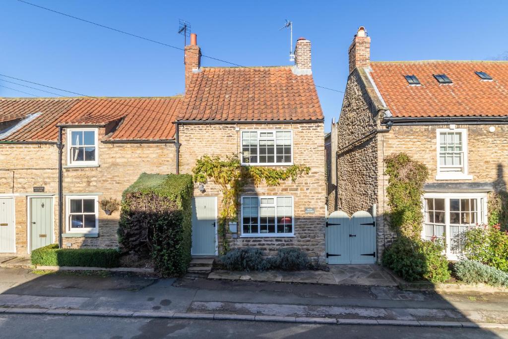 una fila de casas de ladrillo con puertas blancas en Dene Cottage, Welburn en Welburn