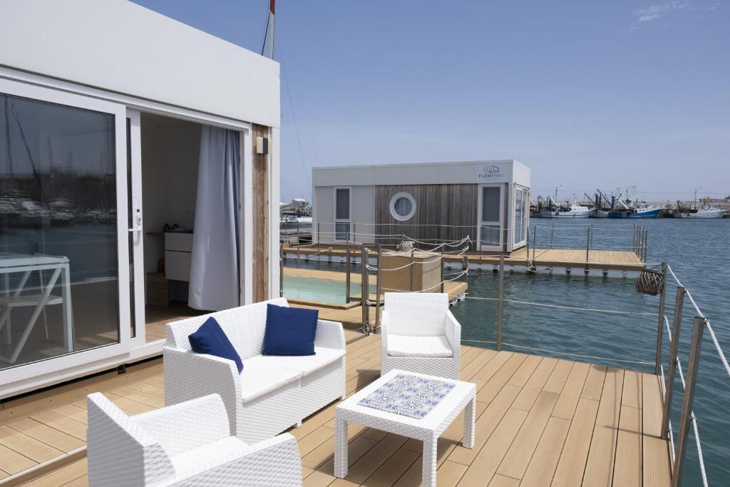 un balcón con sillas blancas y una mesa en un barco en Houseboat Floatart Experience Bisceglie, en Bisceglie