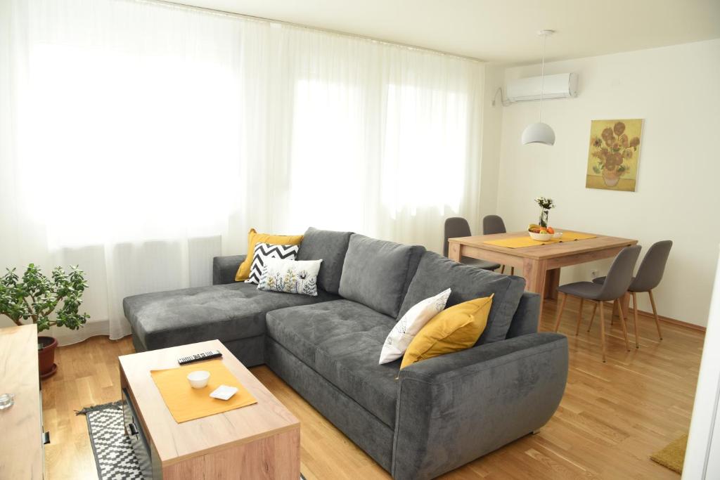 a living room with a gray couch and a table at Suncokret Apartmani Loznica in Loznica