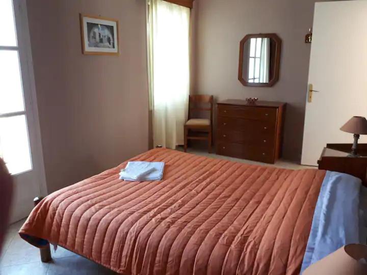 1 dormitorio con 1 cama con manta naranja y espejo en Masouri Square Apartment, en Masouri