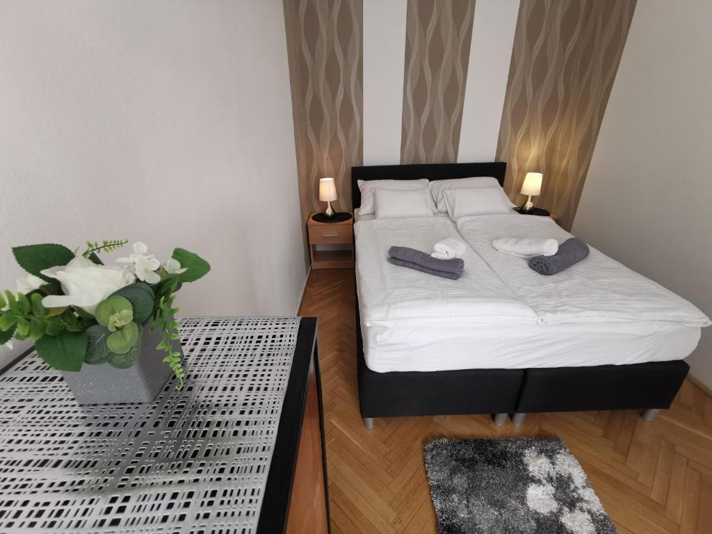 a bedroom with a bed and a table with a vase of flowers at Centrum Apartman in Keszthely