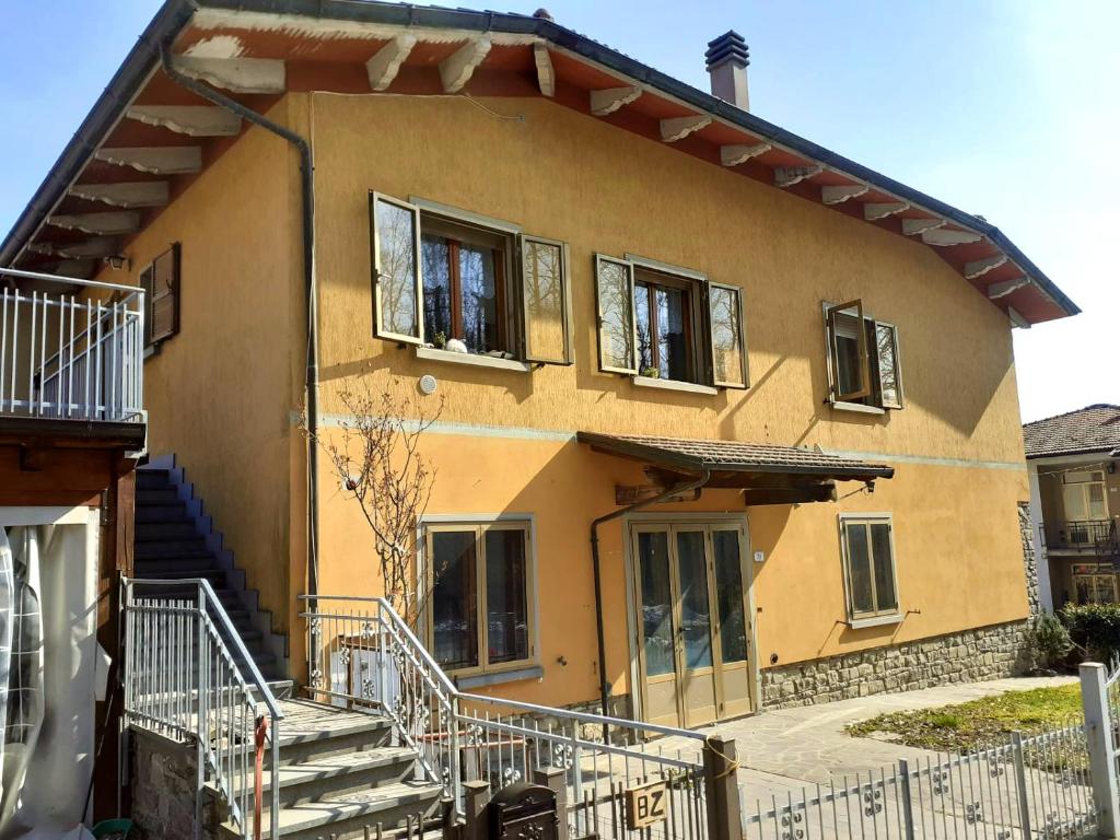 una casa amarilla con escaleras delante en B/B Casa Angela, en Firenzuola