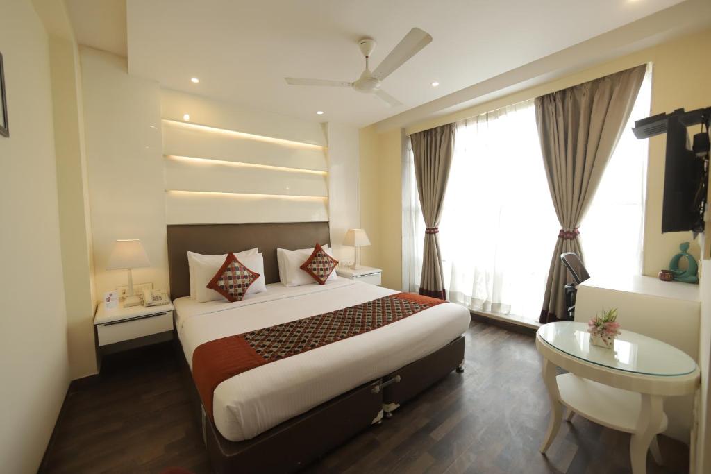 um quarto de hotel com uma cama, uma secretária e uma janela em Hotel Picasso Prive Naraina Delhi - Couple Friendly Local IDs Accepted em Nova Deli
