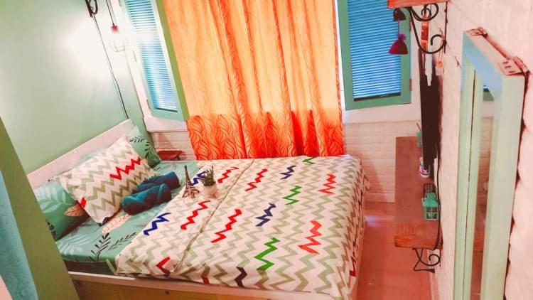 een slaapkamer met een bed met kleurrijke decoraties erop bij French Nest at Baguio- Megatower Residences in Baguio