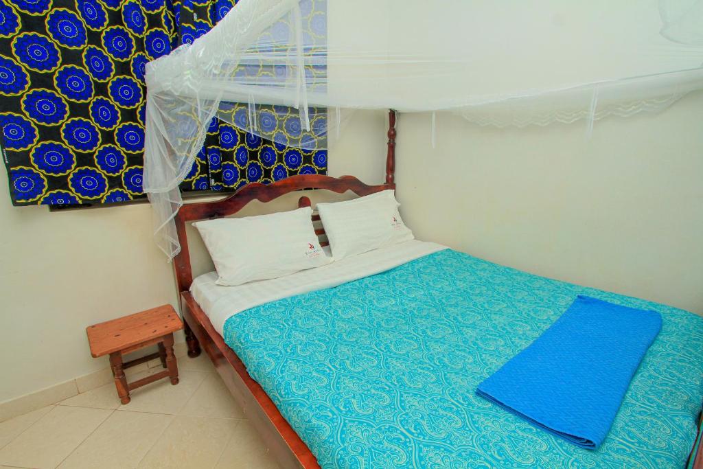 a small bedroom with a bed with a blue and white sheets at Richy Hotels and Safaris in Mbale