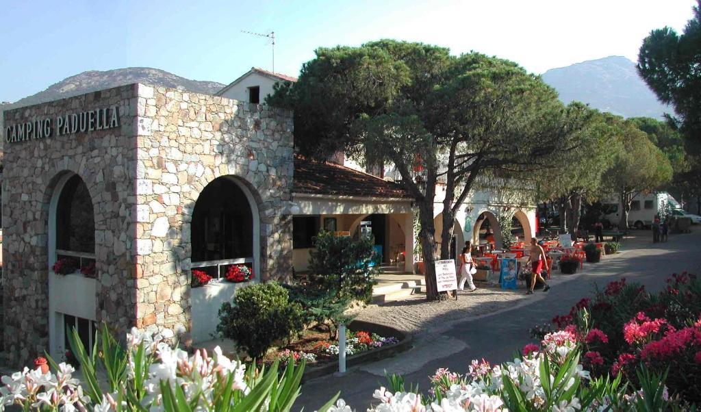 un bâtiment en pierre avec des fleurs devant lui dans l'établissement Camping Paduella, à Calvi
