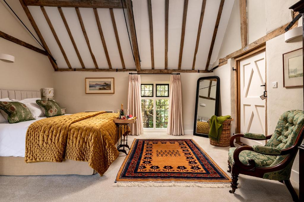 um quarto com uma cama, uma cadeira e uma janela em The Stables em Kings Cliffe