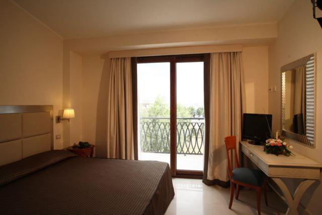 a hotel room with a bed and a desk and a window at Hotel Palace 4S in Crotone