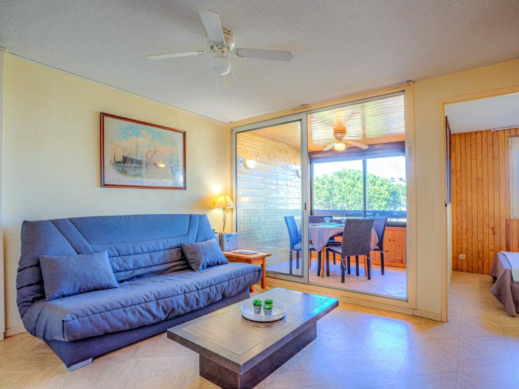 un salon avec un canapé bleu et une table dans l'établissement Apartment Les Mas de La Mer-3 by Interhome, à Saint Cyprien Plage