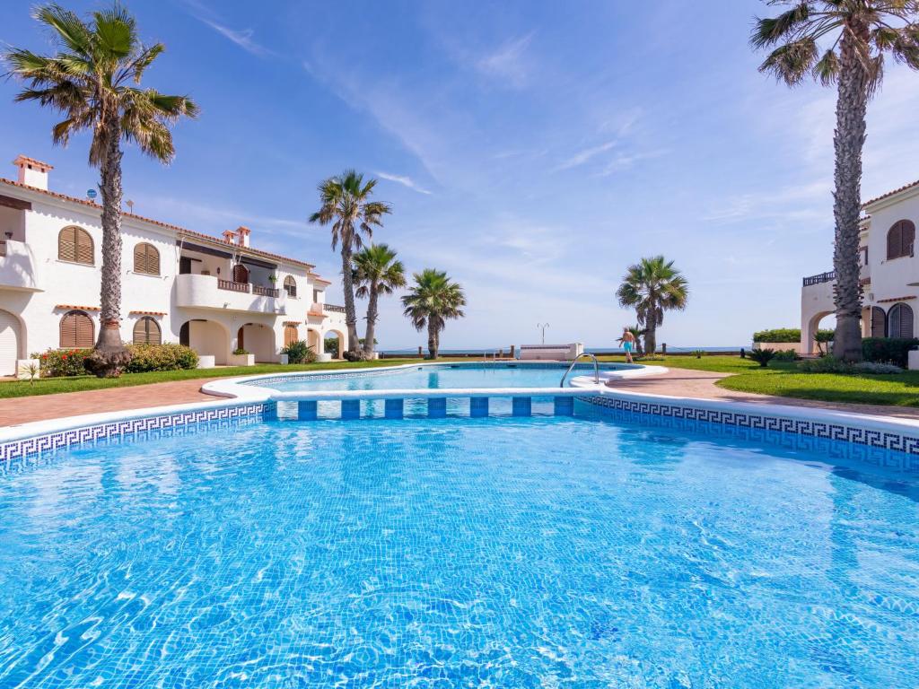a large swimming pool with palm trees in front of a building at Apartment Nueva Playa-1 by Interhome in Les Deveses	