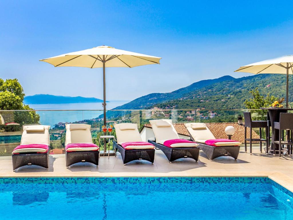 a pool with chairs and umbrellas with a view at Holiday Home Villa Orhidea by Interhome in (( Marčići ))