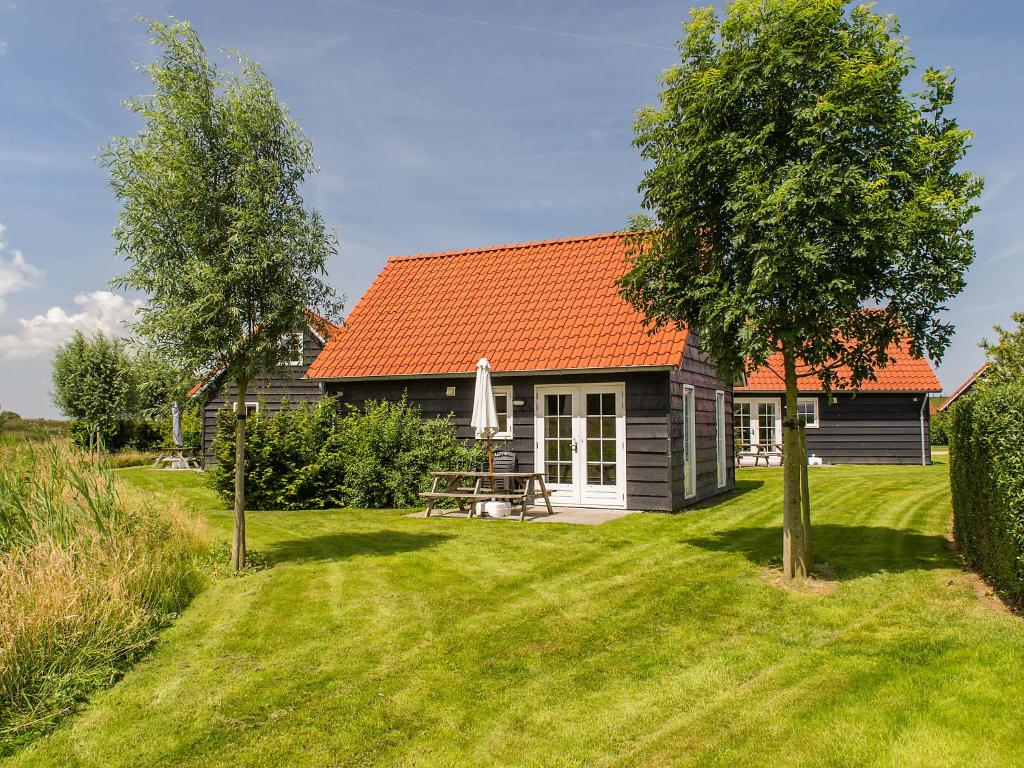 een klein huis met een oranje dak op een erf bij Holiday Home Zeeuwse Cottage Wemeldinge-1 by Interhome in Wemeldinge